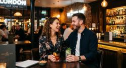 Young couple flirting over cocktails at a stylish London bar, representing casual dating in the UK